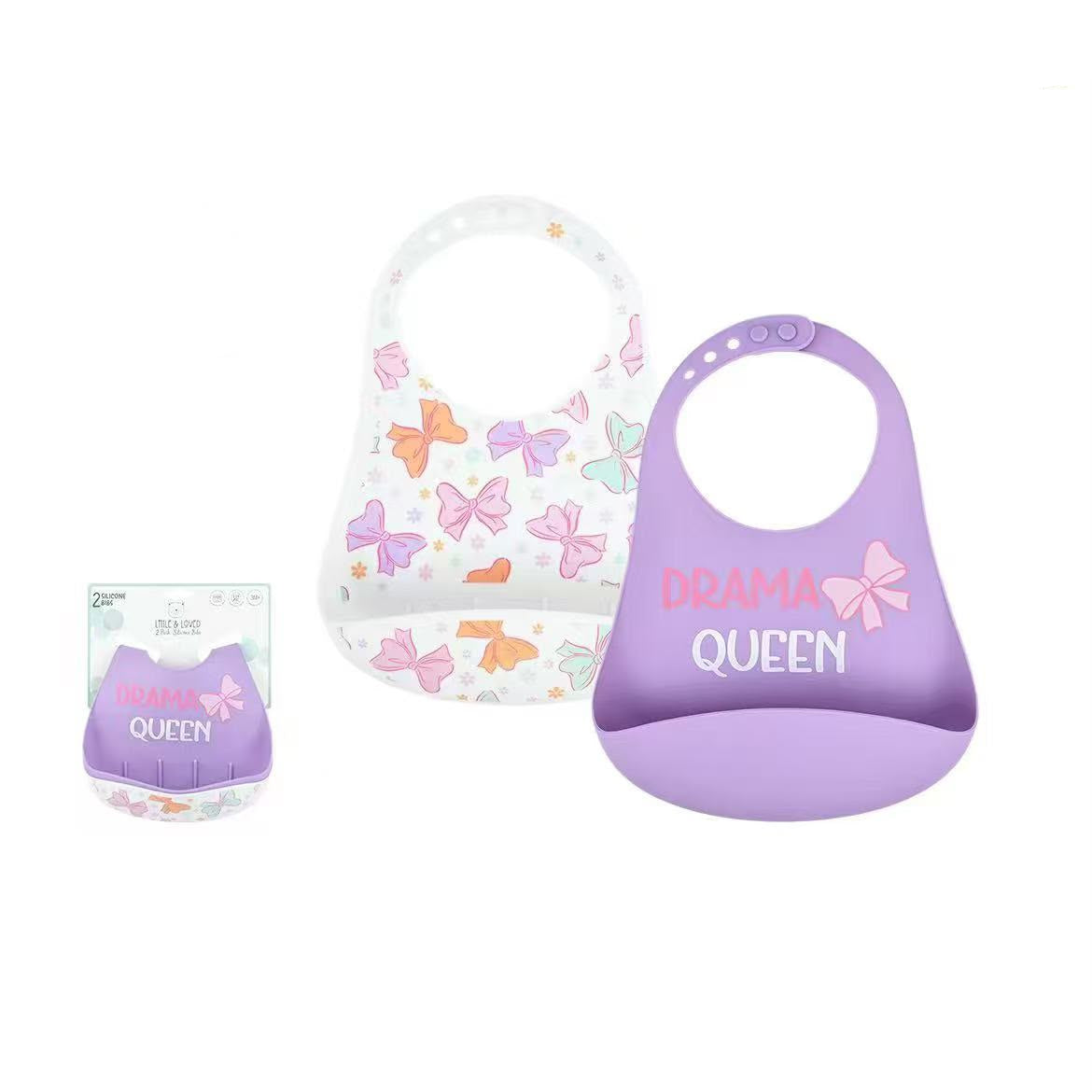 Two silicone baby bibs shown on a white background, one white with pastel butterfly prints and one lavender purple with 'DRAMA QUEEN' text and a bow graphic. A small packaged version of the purple bib appears at left.