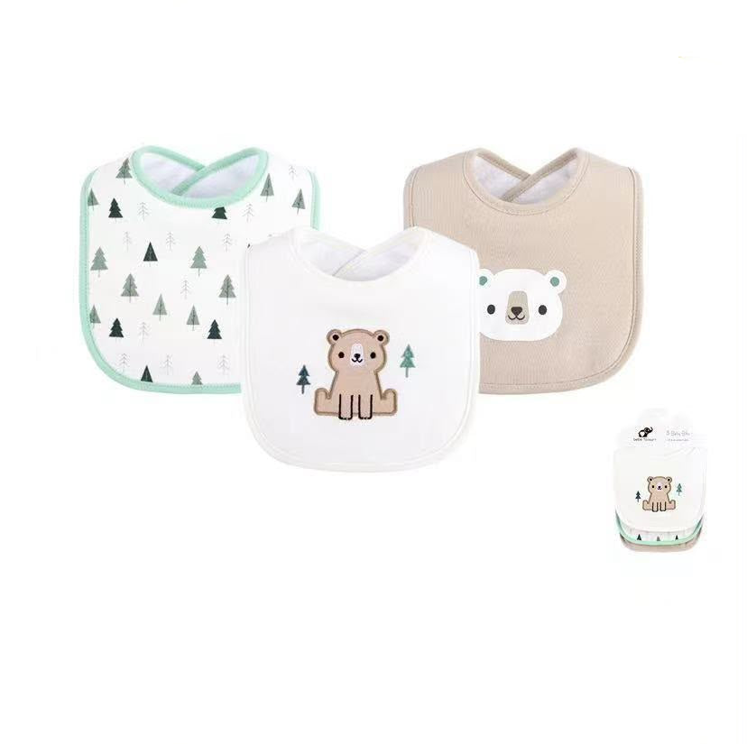 Three baby bibs shown on a white background with product text and a small packaged view. The set includes a mint-edged white bib with dark green tree prints, a white bib with a brown bear and small trees, and a beige bib with a white bear face.