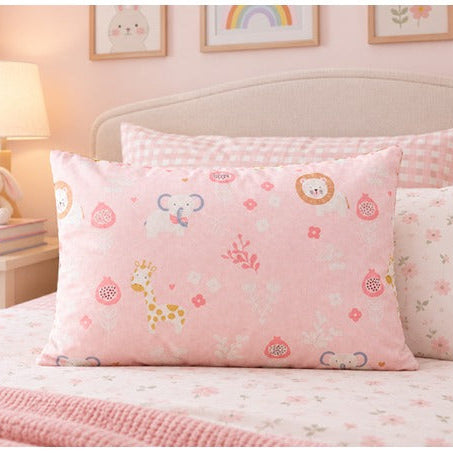 A pink decorative pillow with a cute cartoon animal and floral print, styled on a matching pink bed in a cozy, softly lit bedroom.